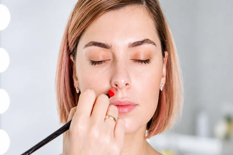 Woman applying makeup and contouring to her nose